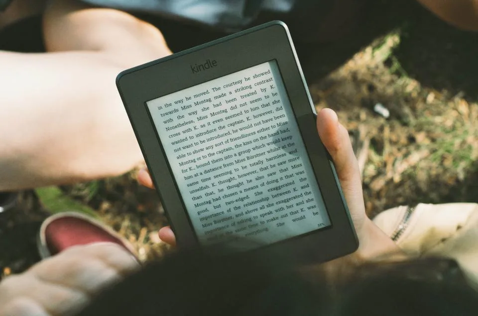 Hands holding an e-reader showing a page of text outdoors