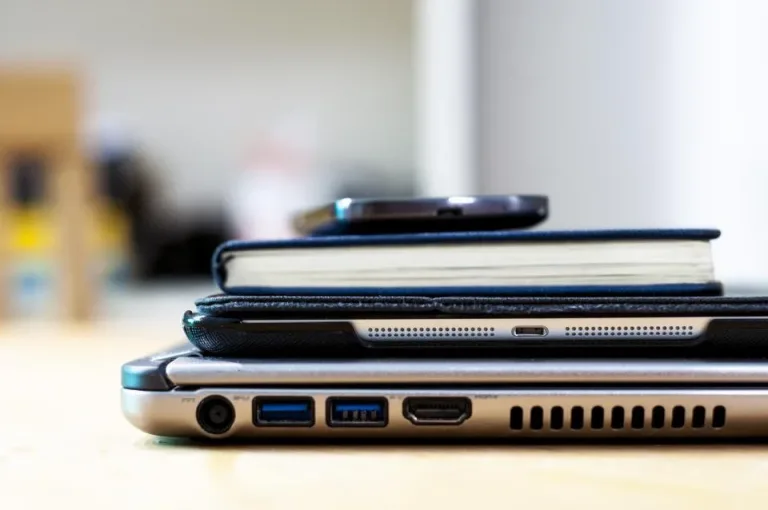 Laptop, tablet in a case and a notebook stacked on a desk