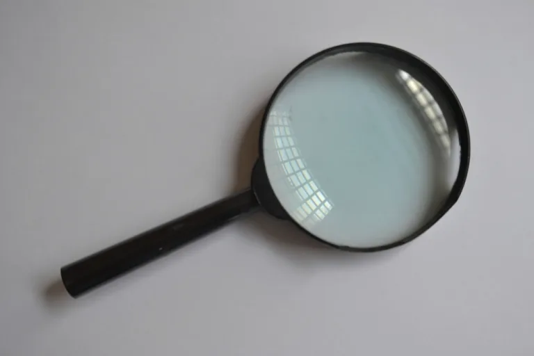 A black magnifying glass lying on a plain gray surface