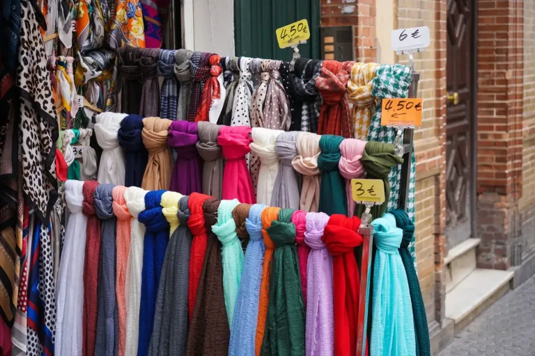 Colorful scarves hanging at an outdoor market stall with small price tags