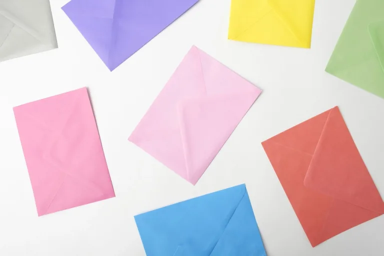 Pastel-colored paper envelopes scattered on a white surface