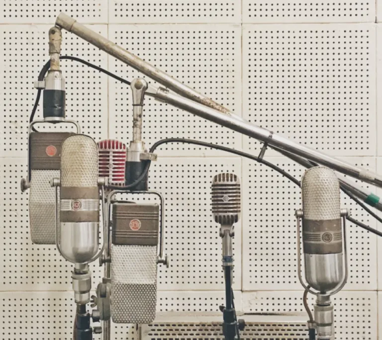 Row of vintage studio microphones in front of a perforated acoustic wall