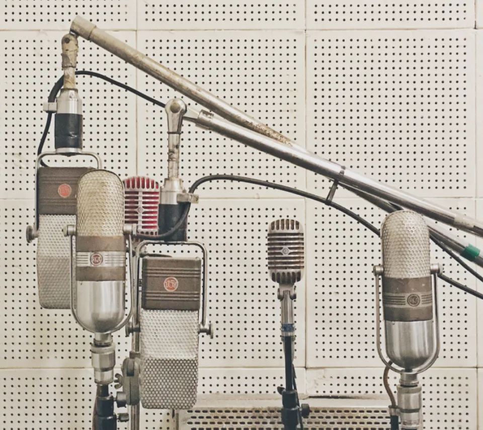 Row of vintage studio microphones in front of a perforated acoustic wall