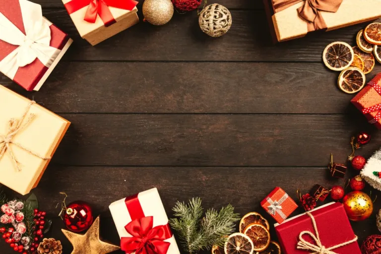 Wrapped gift boxes and ornaments arranged around a dark wooden table