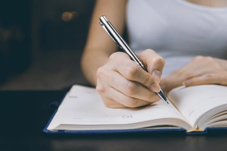 Hand writing with a silver pen in an open paper planner